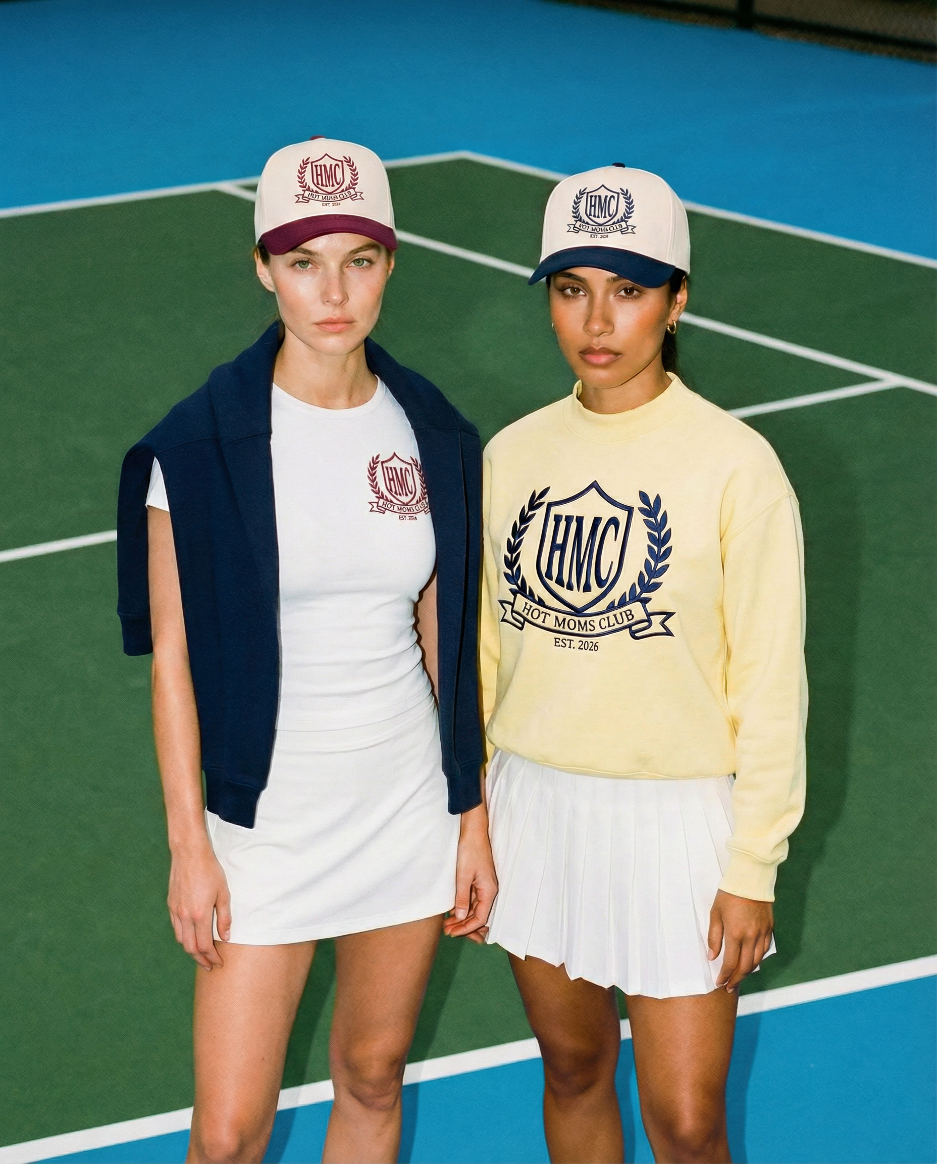 Two women wearing branded caps and clothing on a tennis court