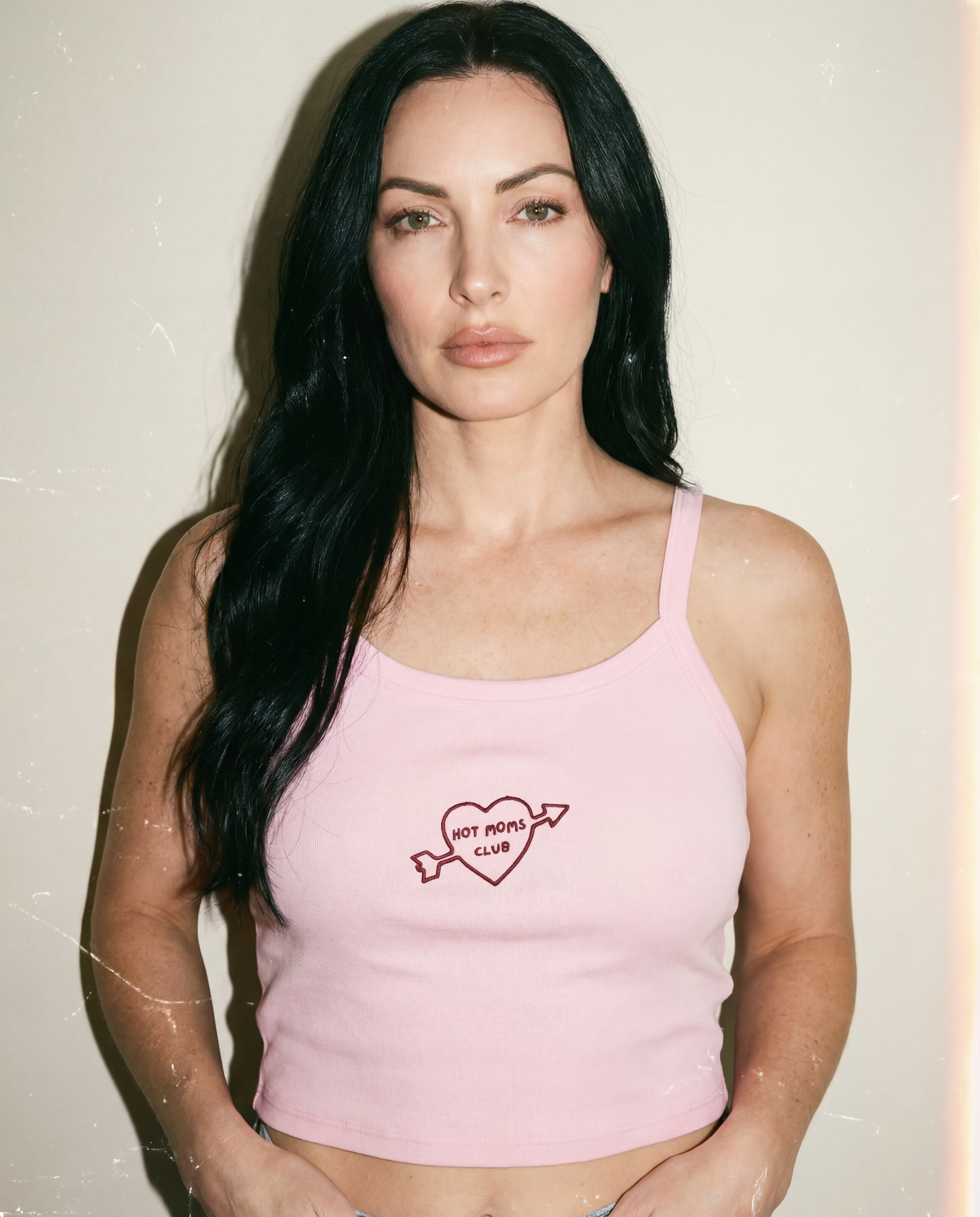 Woman wearing a pink tank top with Hot Moms Club inside of a hear with an arrow through it