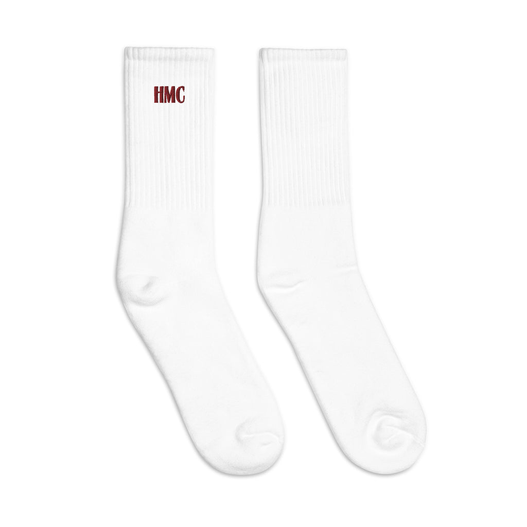 Mockup of two white crew socks with burgundy embroidery logo HMC
