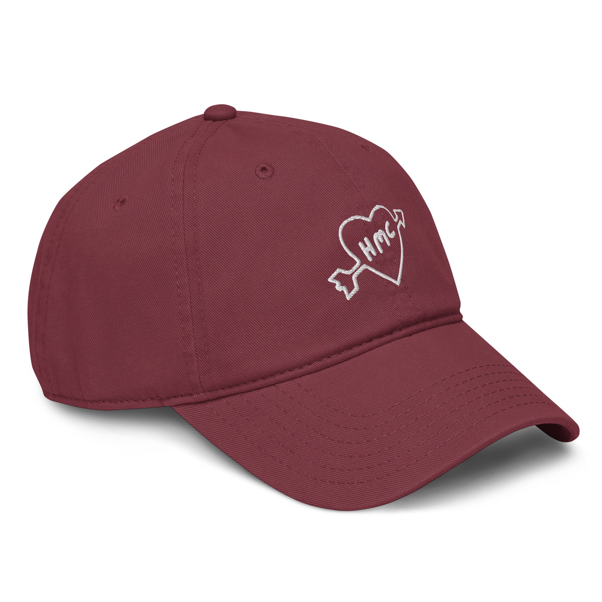 Left side view of a burgundy baseball cap with "HMC" inside of a heart with an arrow through it embroidered in white thread