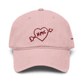 Front view of a pink baseball cap with 'HMC' inside a heart with an arrow through it embroidered in burgundy 