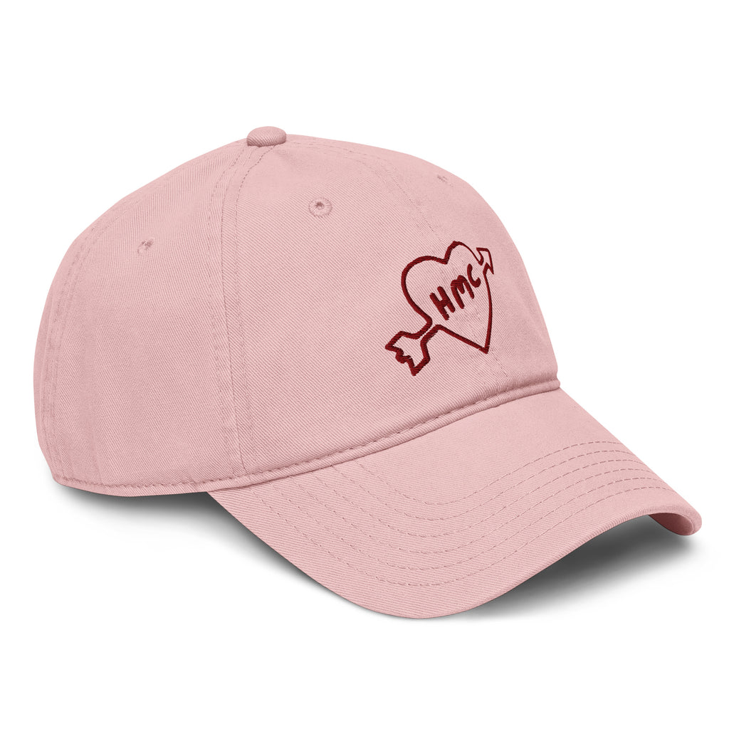 Left side view of a pink baseball cap with 'HMC' inside a heart with an arrow through it embroidered in burgundy 