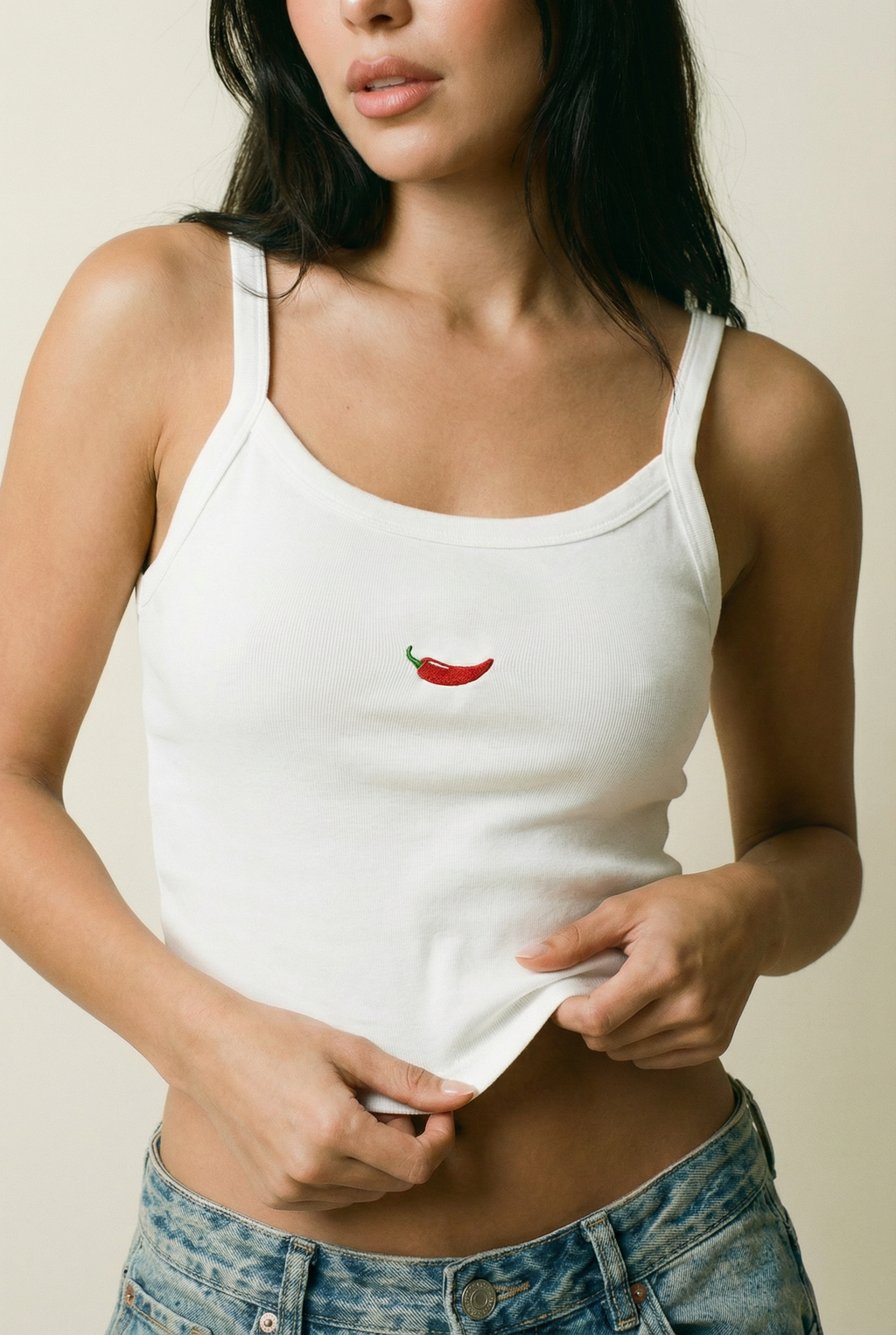 Woman wearing a white tank top with a red chili pepper design.